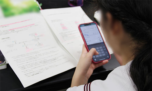 個人のスマホで生物の問題を入力する生徒